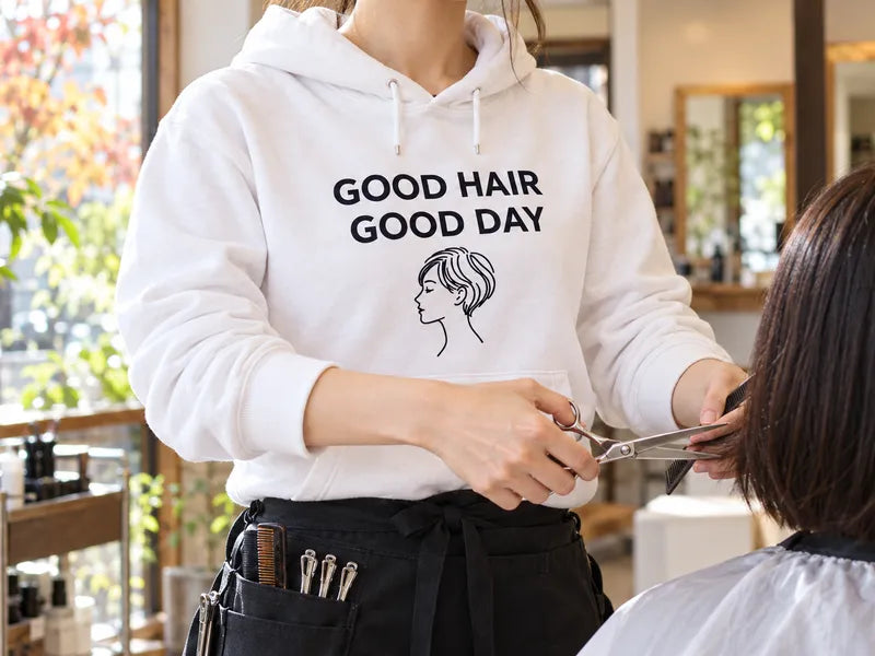 美容室で、GOOD HAIR GOOD DAYの白いパーカーを着たスタイリストがカットしている